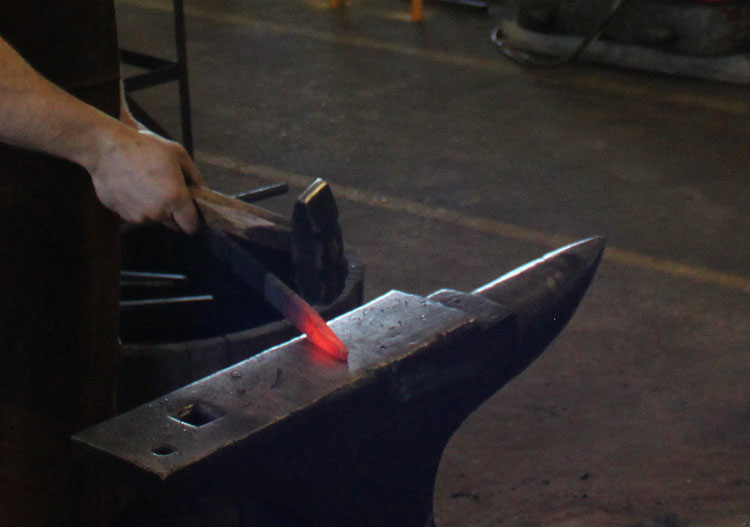  Strike while the iron's hot! Paul Nyborg, blacksmith, pounding out steel on his anvil.